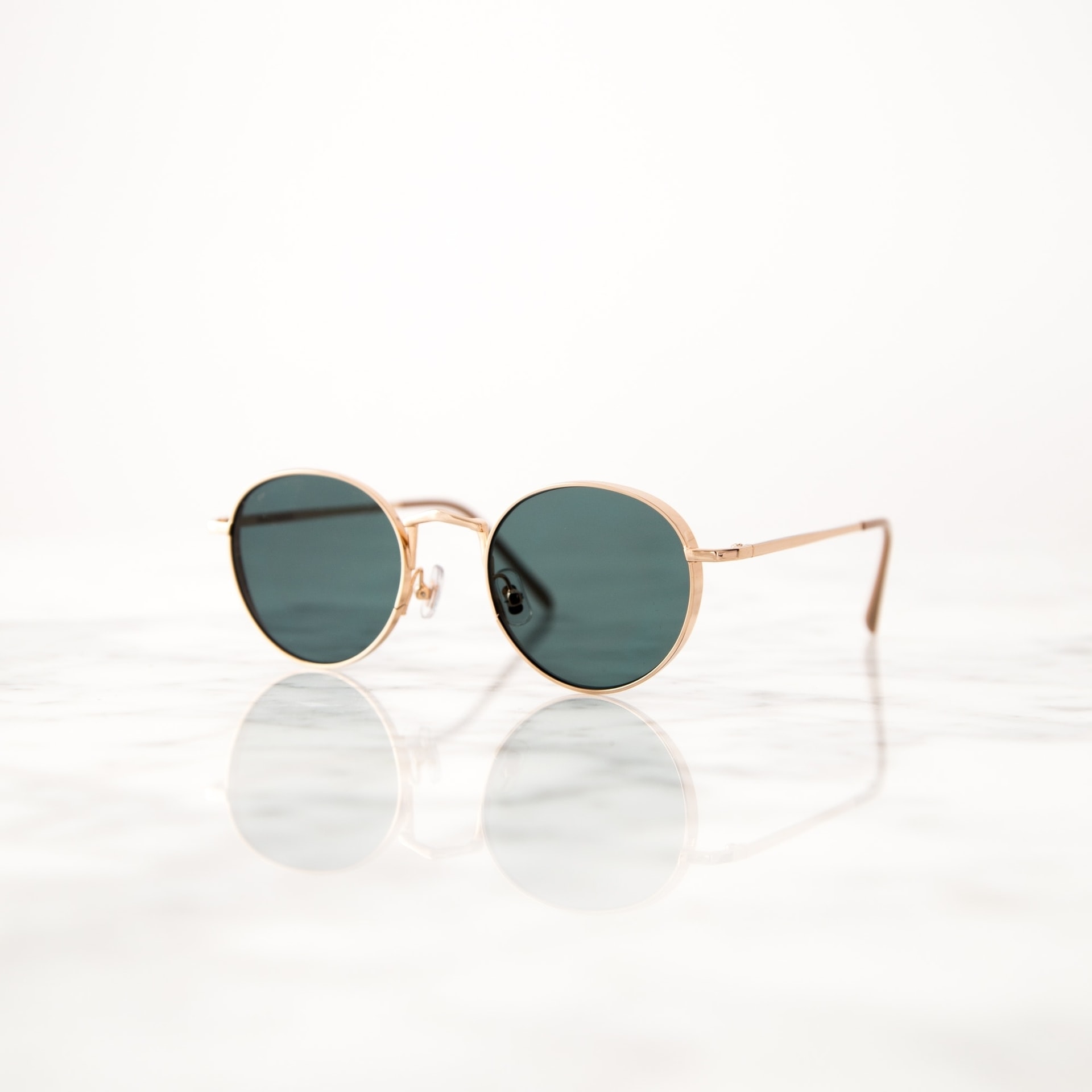 Gold frame sunglasses on reflective marble surface